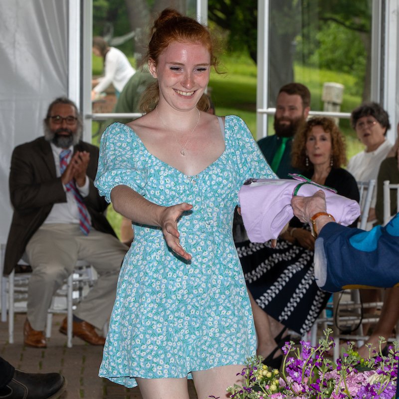 student reaching out to receive gift at graduation