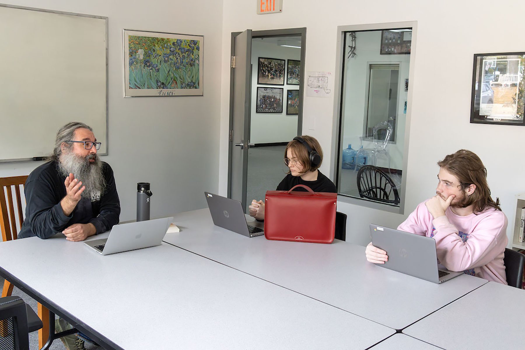 teacher speaking with two students at a table