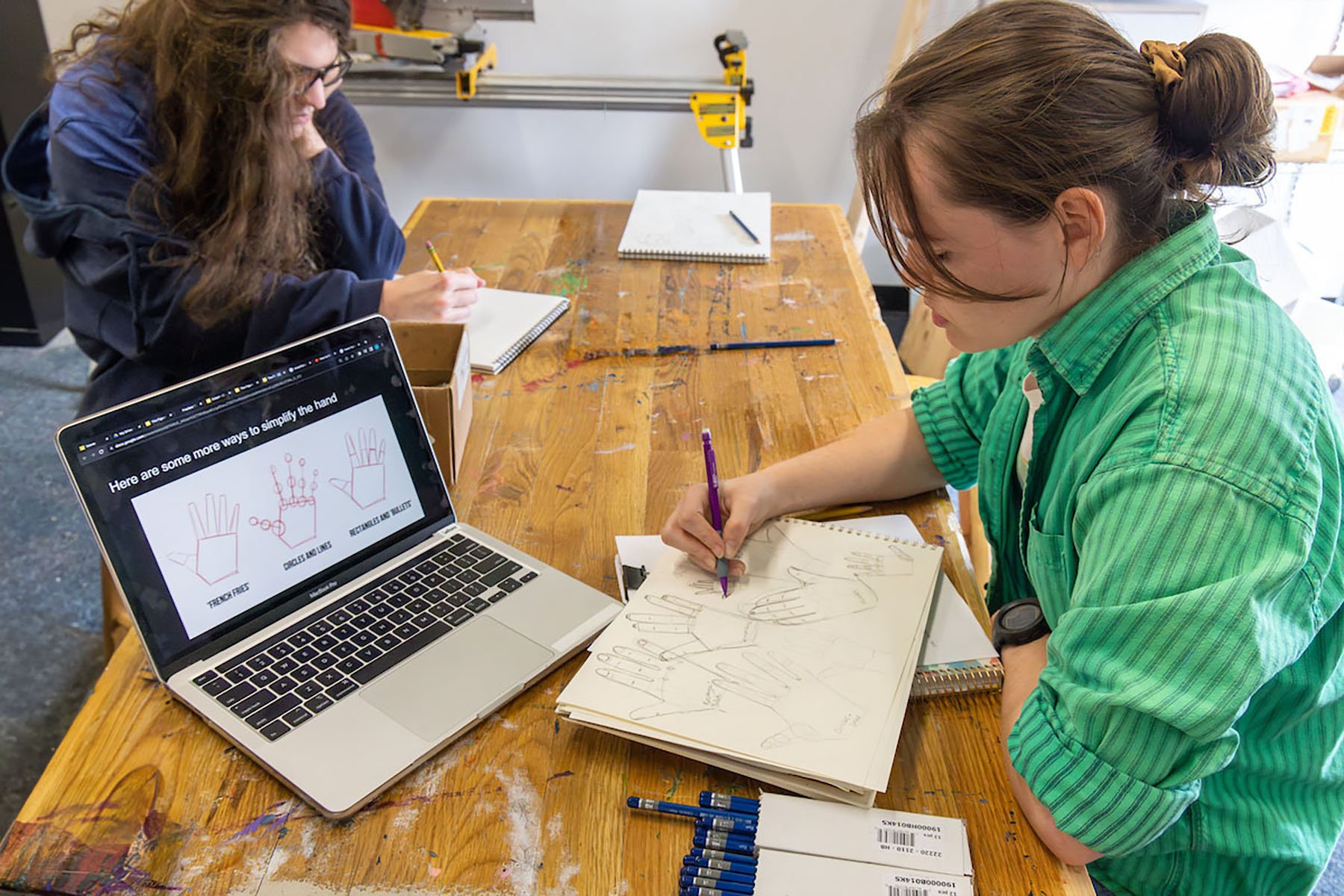 student and teacher at a drawing at a table