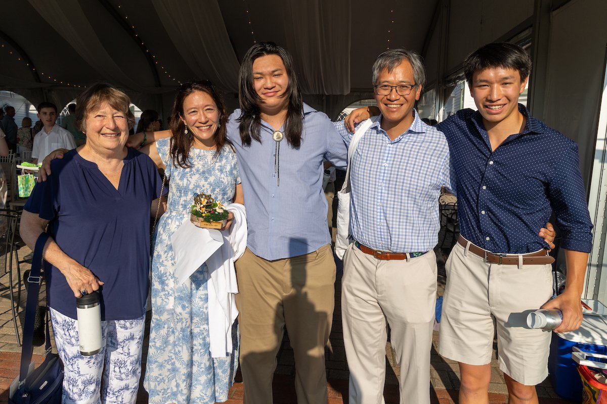 Student graduate standing with family at graduation